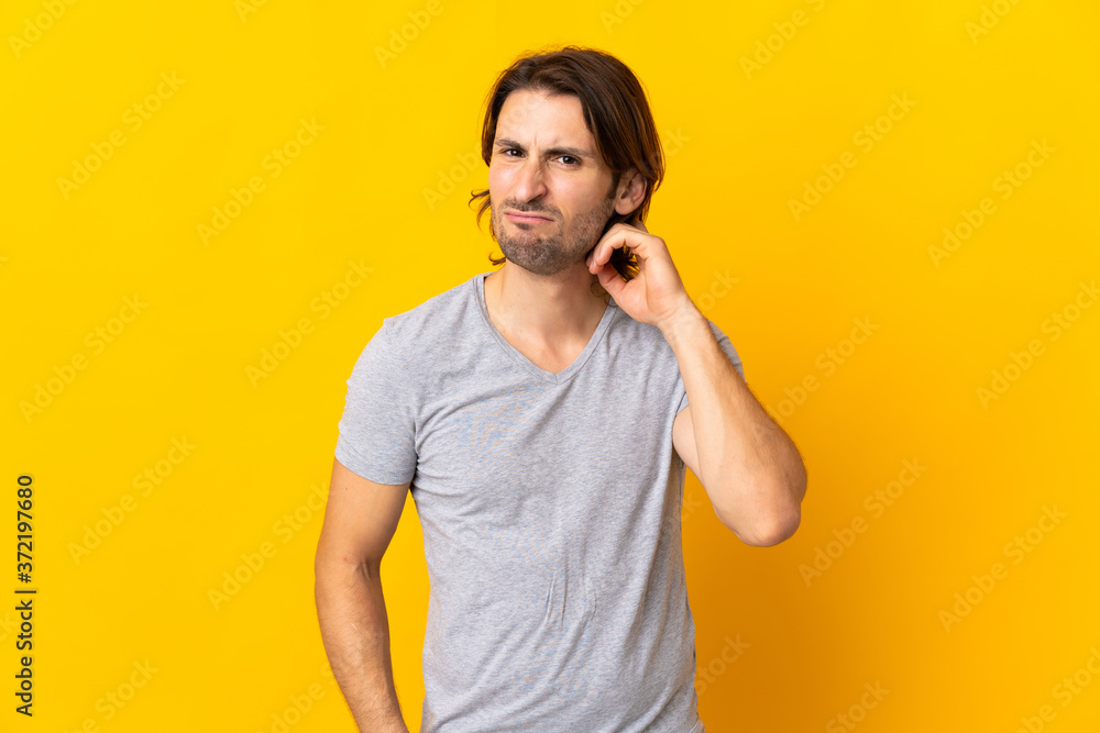 Young handsome man isolated on yellow background having doubts Young handsome man isolated on yellow background having doubts