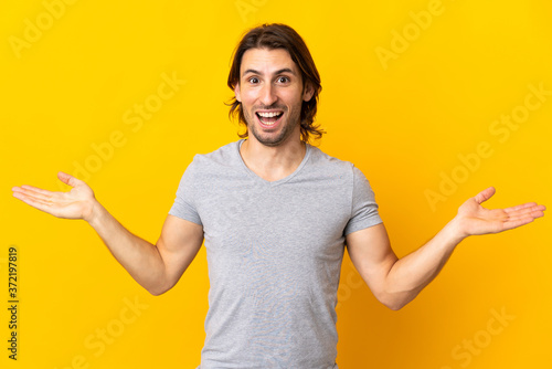 Young handsome man isolated on yellow background with shocked facial expression