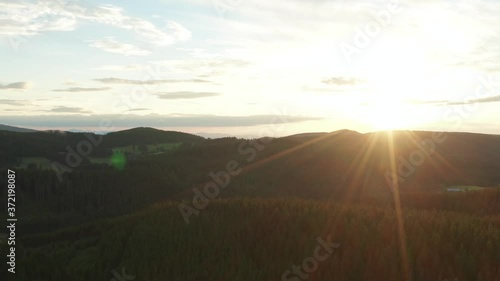 Aerial shot of a sunset over a valley at the blackwood schwarzwald with fir wood forest and little clouds at the sky with lens flares golden hour gernany panorama drone shot photo