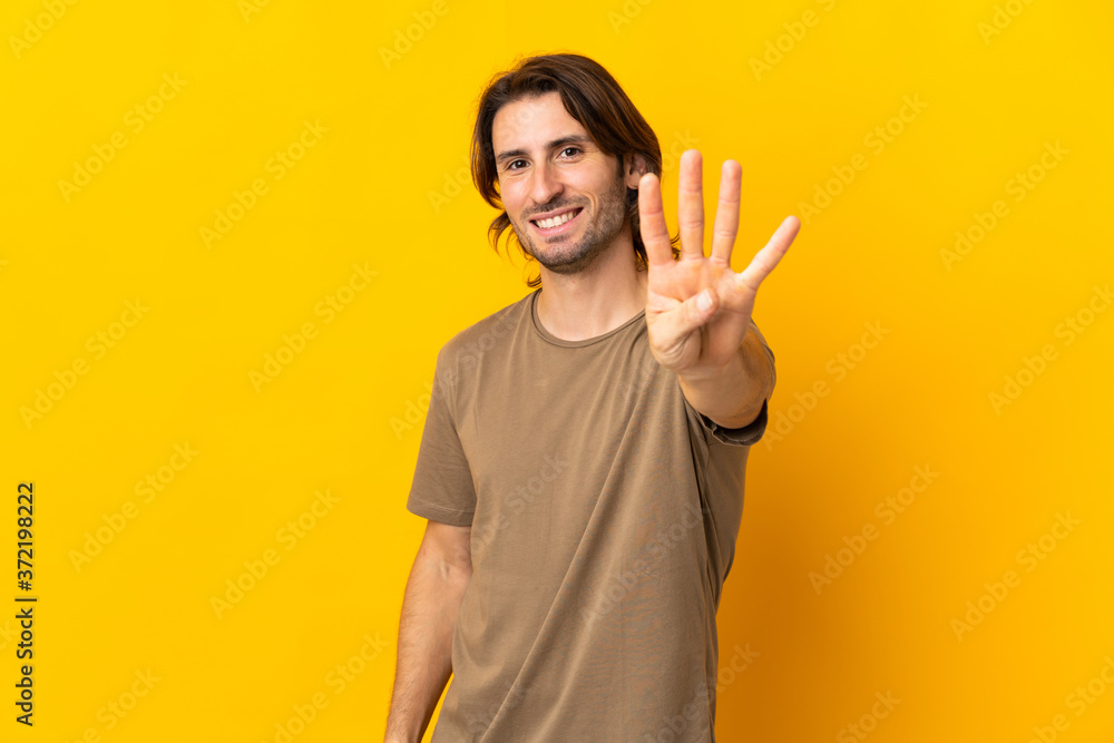 Young handsome man isolated on yellow background happy and counting four with fingers Young handsome man isolated on yellow background happy and counting four with fingers