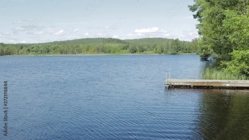Beautiful lake landscape view on sunny summer day. Blue lake water surface on green forest trees and blue sky background. Beautiful lake landscape view on sunny summer day. Blue lake water surface on green forest trees and blue sky background.