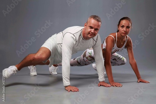 Young sports couple engaged in fitness on a gray background