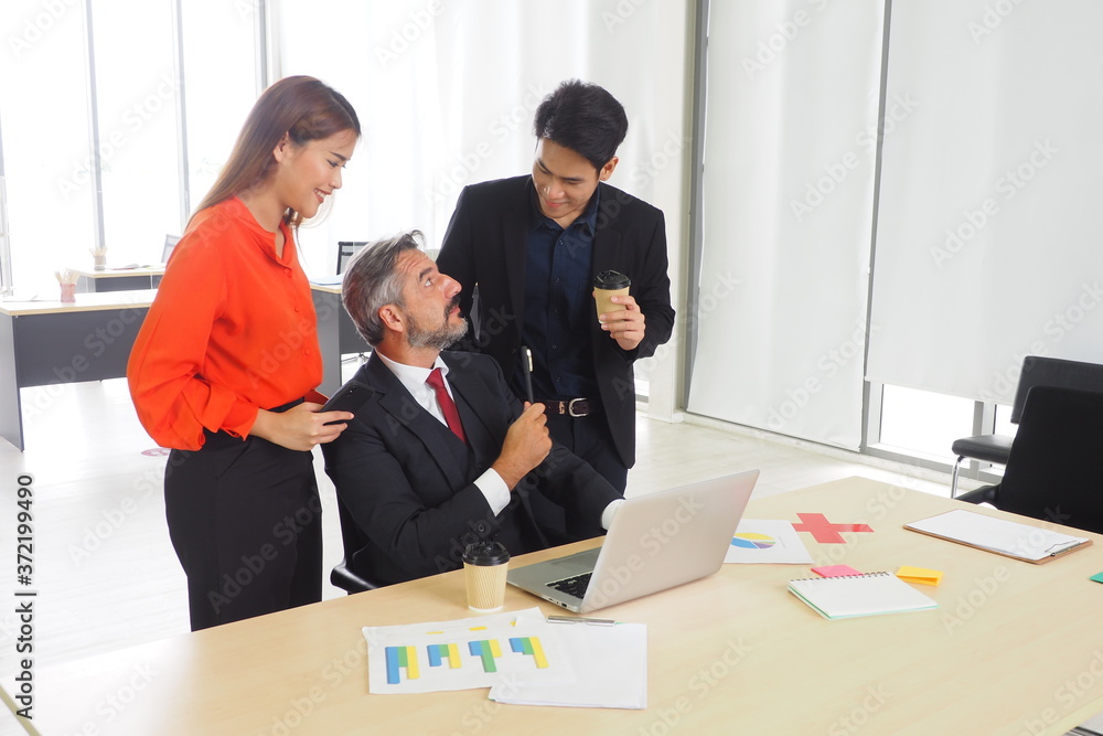 Fototapeta premium Senior male manager meeting and talking with his colleagues in the team in casual style Happy working lifestyle at the office and business discussion concept