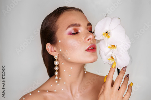 Fotografía Tender woman with glowing makeup on perfect skin smelling scent of orchid flower