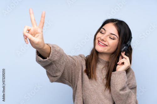 Young brunette woman over isolated blue background listening music and singing