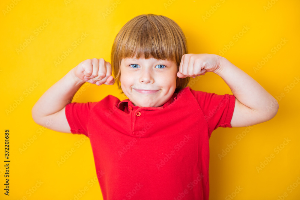 Portrait of a strong boy showing the muscles of his arms on yellow background Portrait of a strong boy showing the muscles of his arms on yellow background