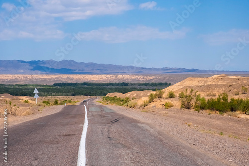 Road in Charyn national park in Kazakhstan. Clouds background. Beautiful sand stone formations. Soil errosion. Travel in Kazakhstan concept.