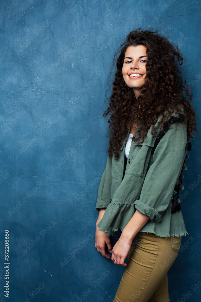 young pretty woman with curly brunette hair posing cheerful on blue background, lifestyle people concept young pretty woman with curly brunette hair posing cheerful on blue background, lifestyle people concept