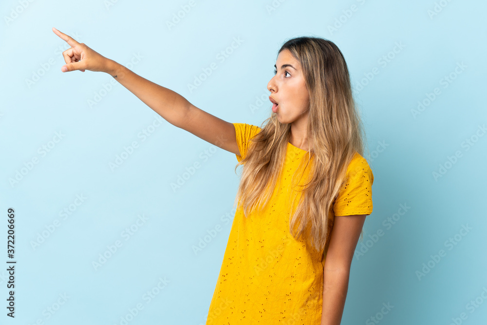 Young hispanic woman over isolated blue background pointing away Young hispanic woman over isolated blue background pointing away