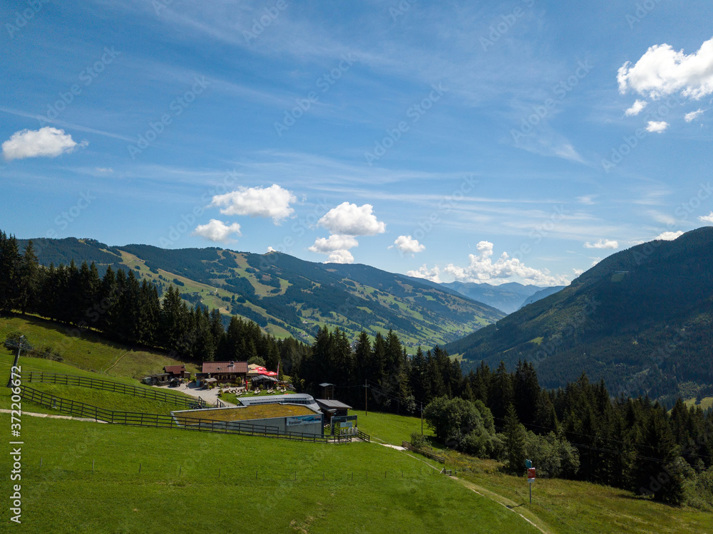 Aerial view on cozy hut with mountain panorama from Hinterglemm to Saalbach in the Alps in Austria. on a sunny summer day.