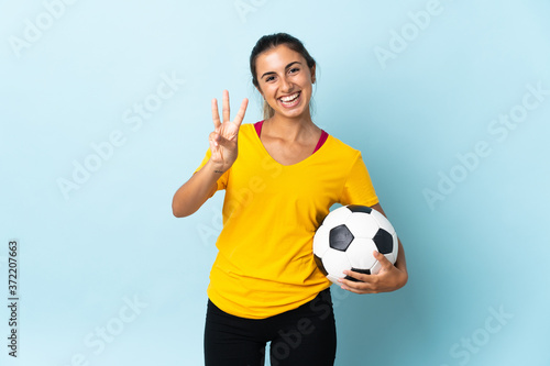 Young hispanic football player woman over isolated on blue background happy and counting three with fingers © luismolinero