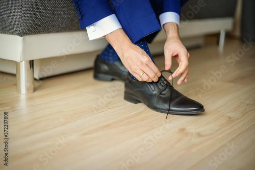 Groom is wearing shoes in blue wedding clothes indoors. The businessman wears shoes © okskukuruza
