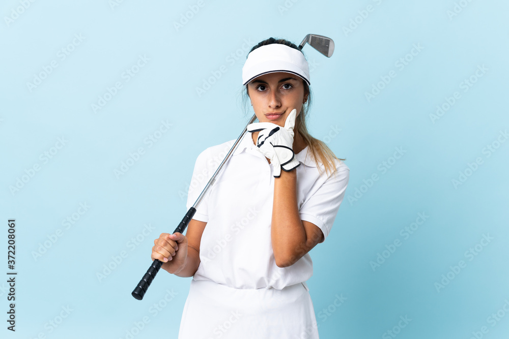 Young hispanic golfer woman over isolated blue wall thinking Young hispanic golfer woman over isolated blue wall thinking