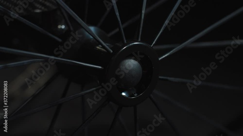 Close up spinning spokes and wheel hub of black wheelchair. Motion control system. Camera moving up