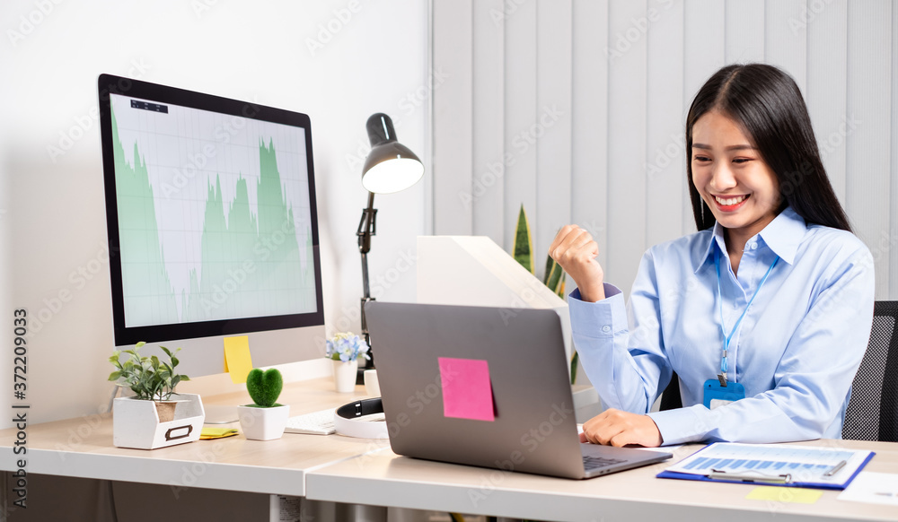 Asian woman working on a laptop with a cheerful and happy smile while working at the office Asian woman working on a laptop with a cheerful and happy smile while working at the office