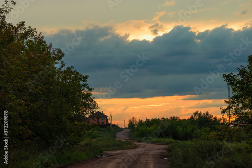 The winding dirt road goes into the horizon against the cloud sky.