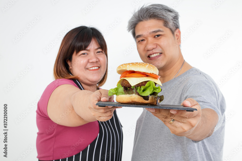 Fat Asian Couple Smile Happy Hold the hamburger together. Eating concept Health, weight loss Fat Asian Couple Smile Happy Hold the hamburger together. Eating concept Health, weight loss