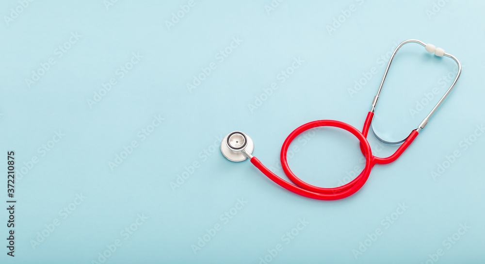 Fototapeta premium Red stethoscope on blue color background. Concept of medicine and health care Pulmonology Cardiology . Top view copy space for text. Long web banner