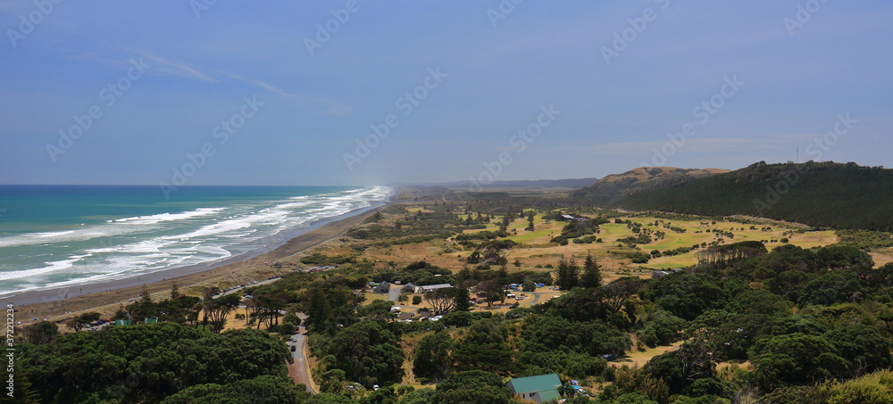 Panoramic view on a beautiful summer day of Muriwai Regional Park, from Mitchelson Lookout, with waves breaking and the black sand beach at Muriwai Beach, on the west coast of Auckland, New Zealand