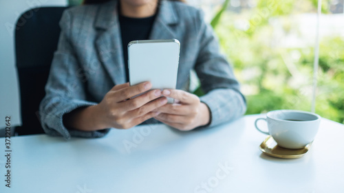 Closeup image of a businesswoman holding and using mobile phone in office