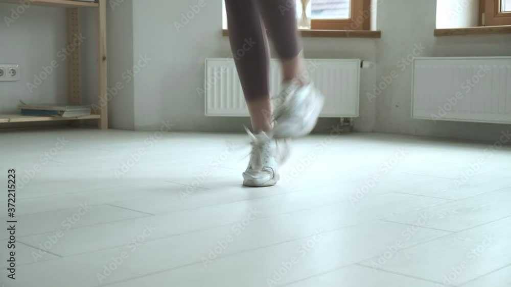 Close-up of female feet in sneakers jumping on floor whilst using skipping rope. Athlete woman doing jump exercise. girl doing sports, fitness training at home. Healthy lifestyle, leisure, weight loss Close-up of female feet in sneakers jumping on floor whilst using skipping rope. Athlete woman doing jump exercise. girl doing sports, fitness training at home. Healthy lifestyle, leisure, weight loss