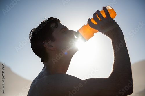 Fitness man silhouette drinking water from a bottle