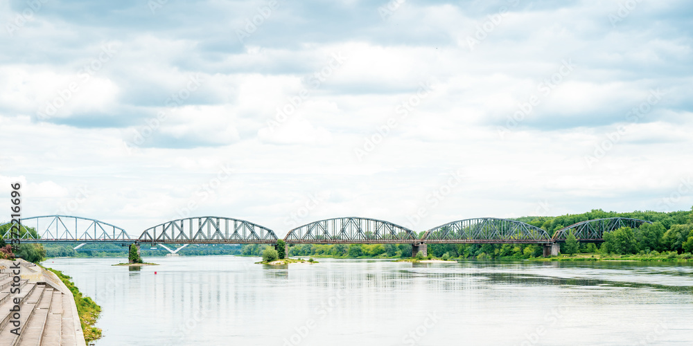Fototapeta premium Photography road bridge over Vistula River in Torun (Pilsudski Bridge), Poland. Heavy rusty steel old industrial vehicle overpass. Landscape city view from boulevard.