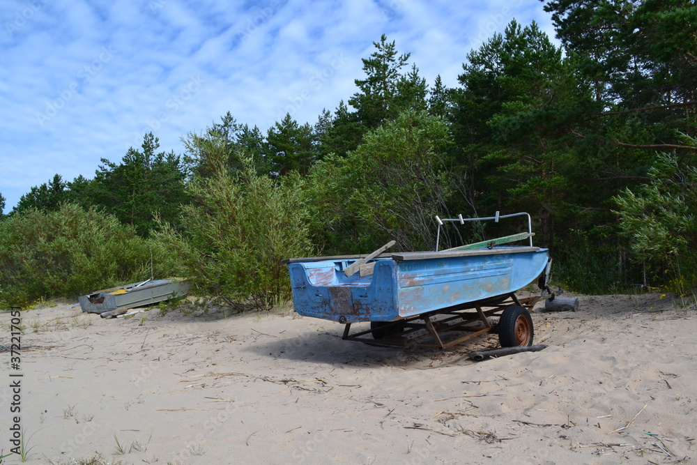 Fototapeta premium an old boat on the sandy shore of the lake on a summer day