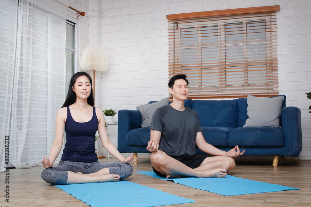 Asian couples do yoga exercises at home together during COVID-19 and social distancing. Concept of keeping healthy. copy space Asian couples do yoga exercises at home together during COVID-19 and social distancing. Concept of keeping healthy. copy space