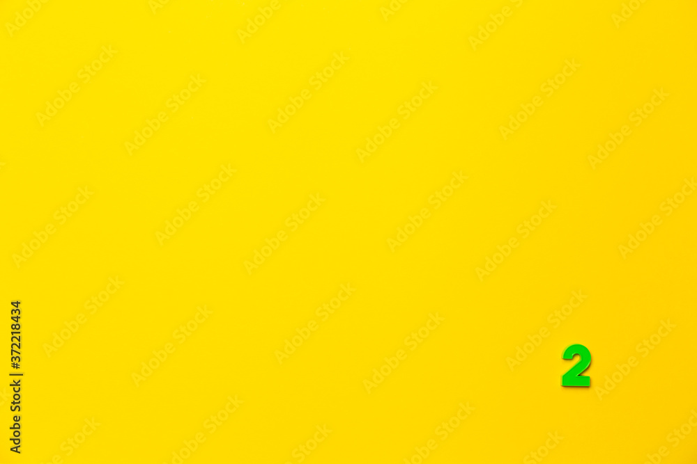 Number 2, two, the second of the plastic baby green toy number is located in the lower right corner on a yellow paper background. Banner on the topic of page numbering, timing or day in the calendar Number 2, two, the second of the plastic baby green toy number is located in the lower right corner on a yellow paper background. Banner on the topic of page numbering, timing or day in the calendar