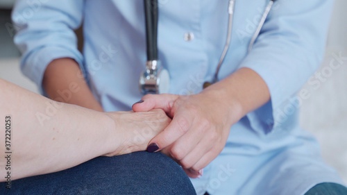 Doctor holds the elderly patient's hands and calms her down