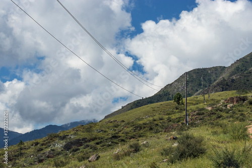 Wooden poles of power lines stand on the hills in the countryside. Travel the Altai year during the summer months. 