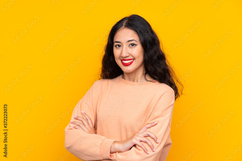 Obraz premium Spanish Chinese woman over isolated yellow background with arms crossed and looking forward