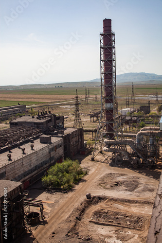 Old outdated soviet metallurgy factory (plant) buildings and rusted chimneys on blue sky and mountain background. Taraz city, Kazakhstan. photo