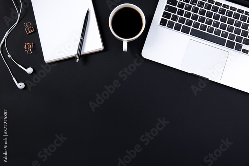 black table with laptop, headphones and other work accessories with cup of coffee. Top view with copy space for text input.