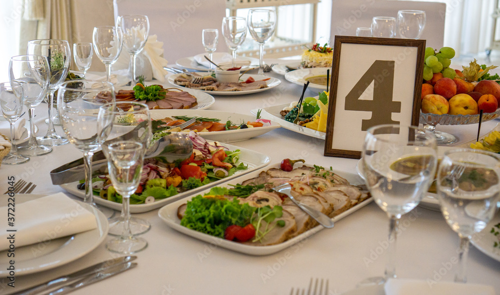 beautiful table setting in light colors with dishes and assorted food on a table with a white tablecloth for a party, wedding or other special event. Restaurant business and service industry concept. 