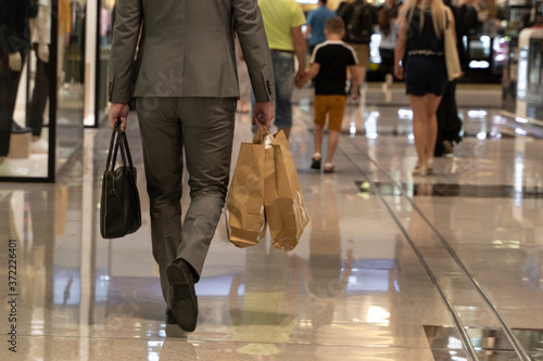 Young man shopping in the mall with many shopping bags in his hand.