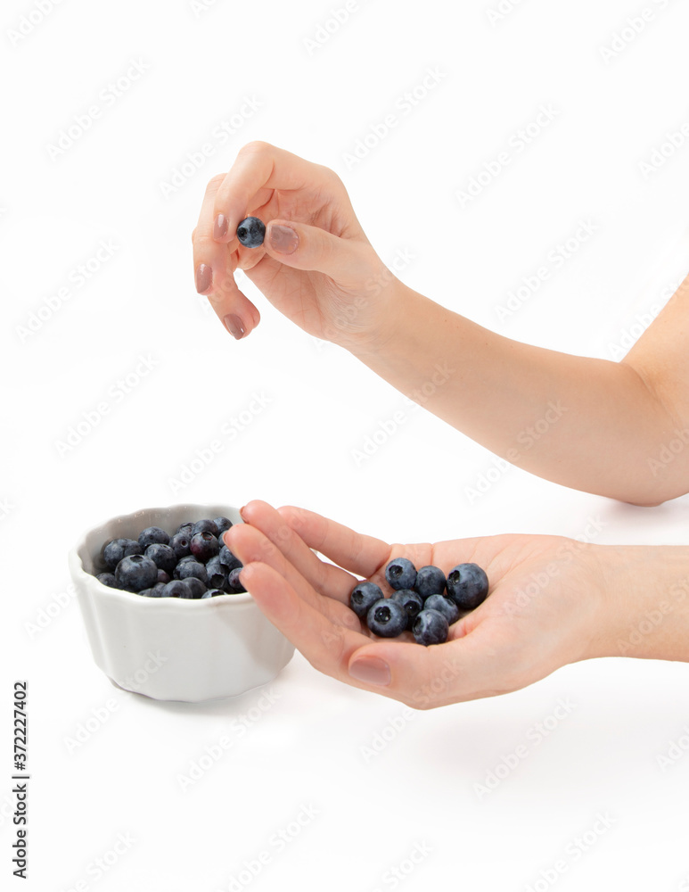 Hand picking a blueberry over a bowl full of organic fresh berries. Summer fruit for healthy diet Hand picking a blueberry over a bowl full of organic fresh berries. Summer fruit for healthy diet