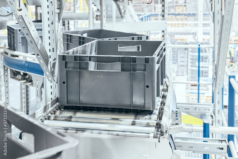 Modern roller conveyor system with plastic boxes, shallow depth of field.