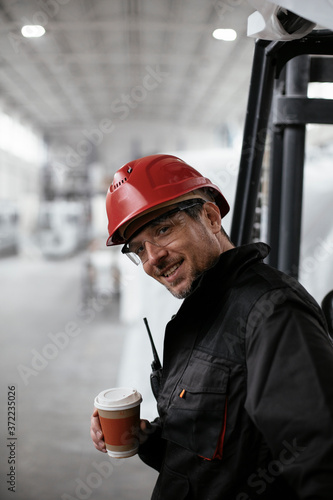 Portrait of worker in factory. Hadnsome man drinking coffee in factory. photo