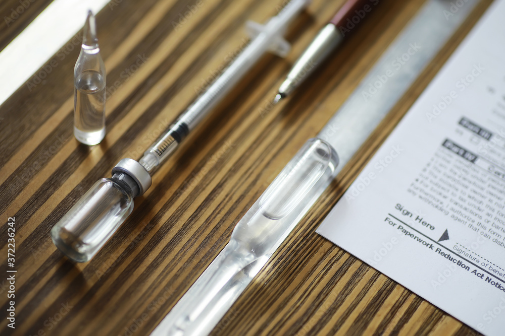 A man signs a medical document. Medical equipment on the table. Stethoscope and ampoules with syringes. Makes notes in the office. Medical center. A man signs a medical document. Medical equipment on the table. Stethoscope and ampoules with syringes. Makes notes in the office. Medical center.