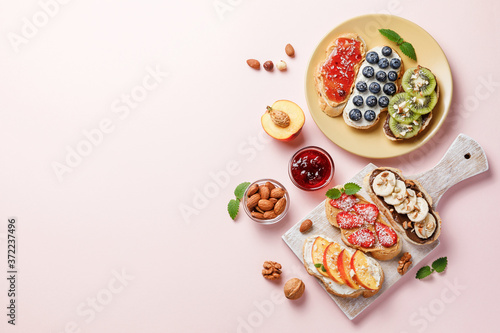 Fototapeta Naklejka Na Ścianę i Meble -  Sweet sandwiches with fruits and berries on pink colorful background.