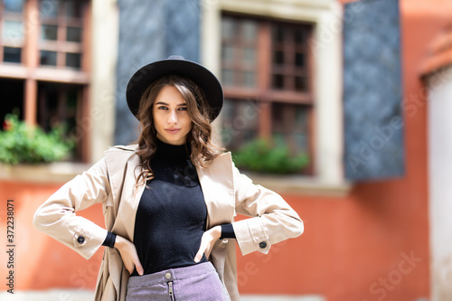 Young fashionable woman in hat and coat posing in street.