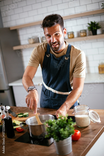 Portrait of handsome man in kitchen. Young man having fun while cooking at home