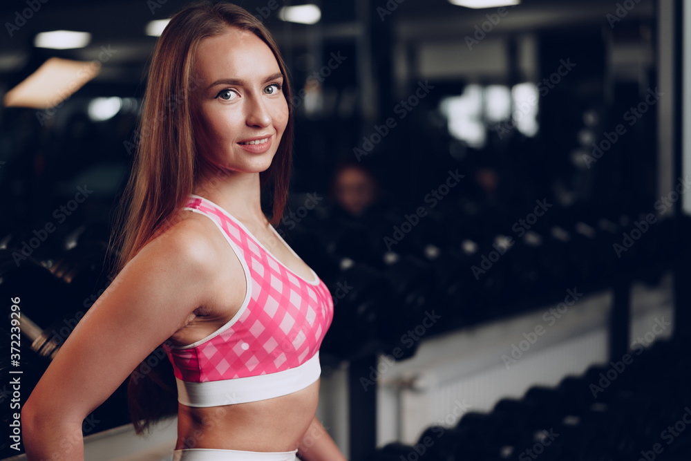 Portrait of a young woman in sportswear posing in a gym