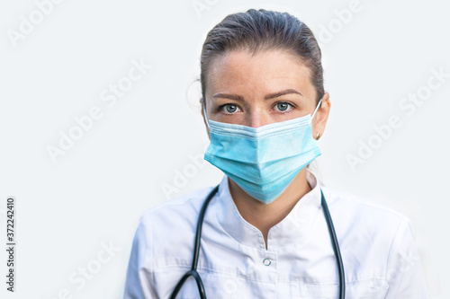 portrait of tired, exhausted young woman doctor with stethoscope, or nurse in mask after work, surgery, procedures on white background in hospital. emotions of medical staff in the clinic