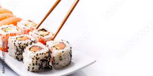 Closeup of sushi roll dish with bamboo chopstick frame isolated on white background. Luxury japanese restaurant dinner with sashimi, maki, surimi and soy sauce on plate.