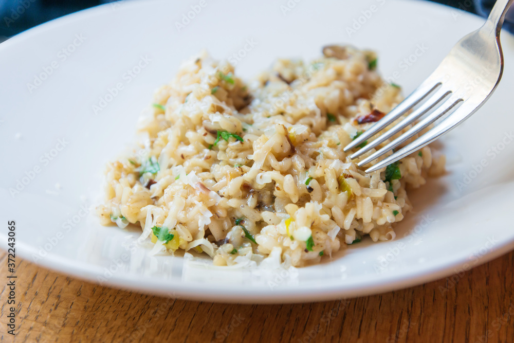 Delicious Italian vegetarian risotto cooked with mushrooms and onions served in white plate. Delicious Italian vegetarian risotto cooked with mushrooms and onions served in white plate.