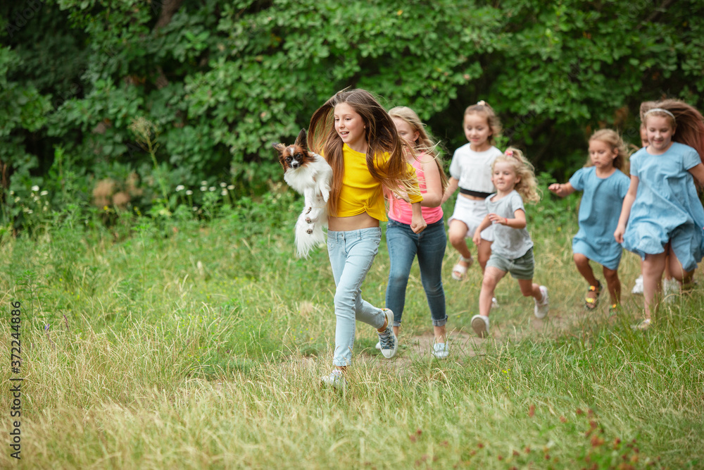 Carefree. Kids, children running on green forest. Cheerful and happy boys and girs playing, laughting, running through green blooming meadow. Childhood and summertime, sincere emotions concept.