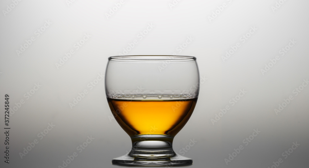 Glass of cognac or whiskey over gradients light background.